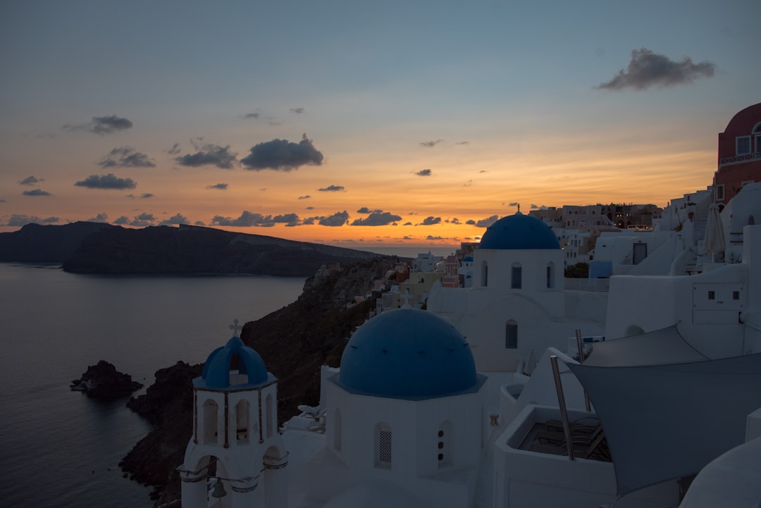 Iconic white-washed buildings and blue domes overlooking the Santorini caldera at sunset